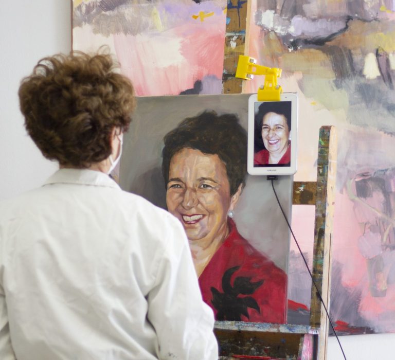 Mujer haciendo un autorretrato al óleo en una escuela de dibujo y pintura muy luminosa y amplia.