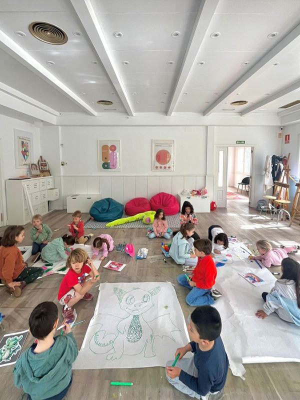 Niños y niñas en una escuela de arte pintando y desarrollando su creatividad libremente en un espacio luminoso y amplio.