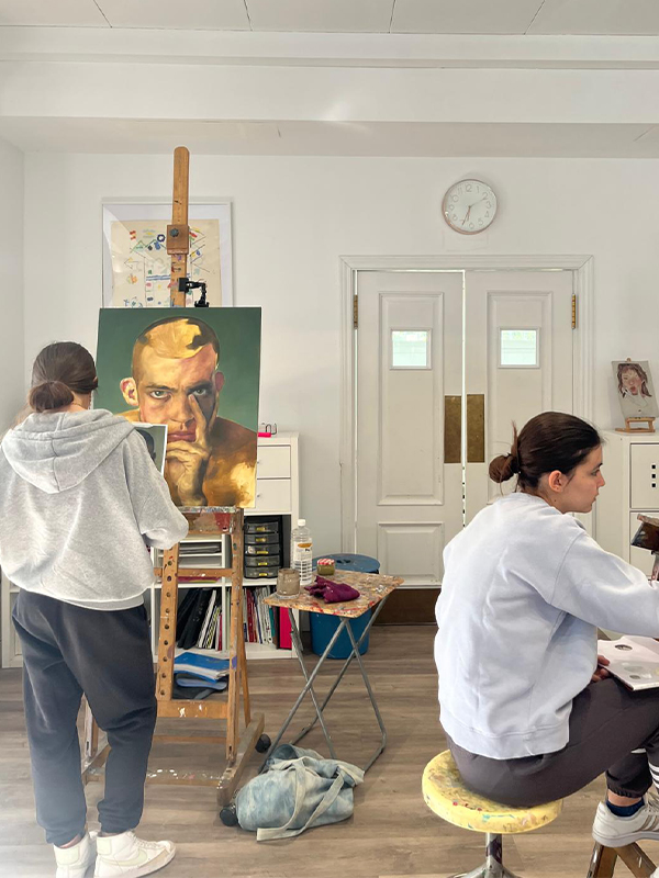 Dos adolescentes pintando un retrato en óleo en una escuela de arte muy amplia y luminosa. Disfrutando de una seguro en el que se reúnen adolescentes para compartir aficiones comunes.