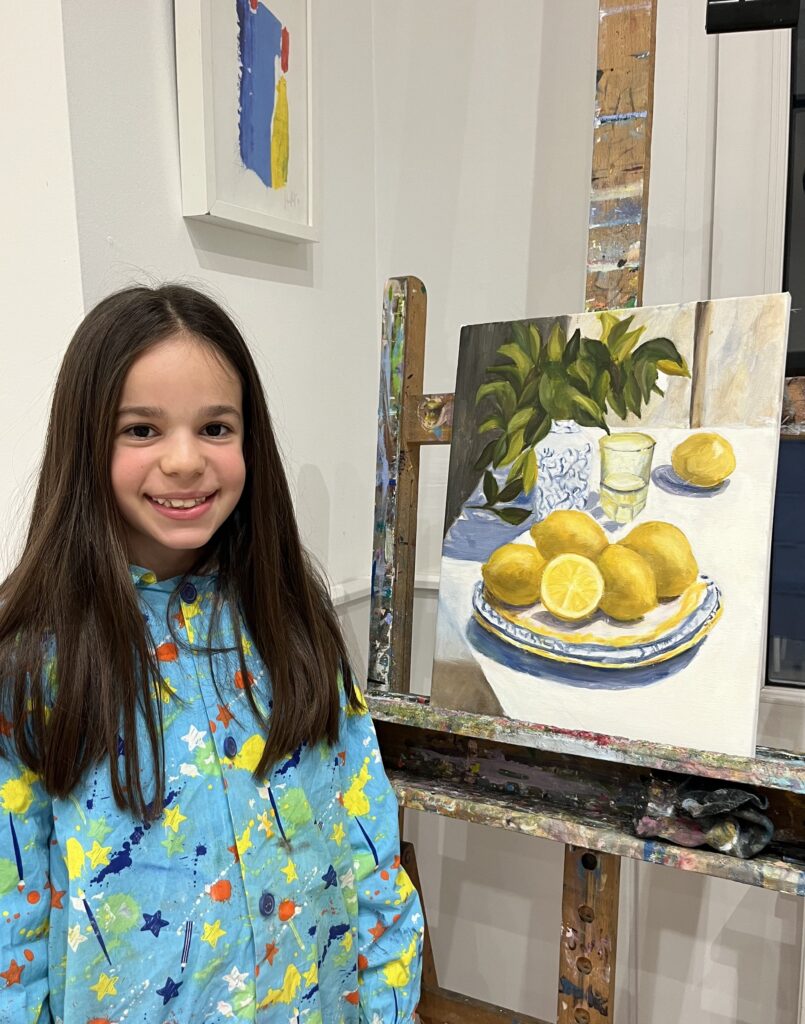 niña con un cuadro hecho en óleo de unos limones en espacio de arte