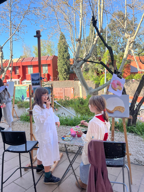 Dos niñas pintando al aire libre en Espacio para el Arte en Torrelodones. Las niñas se divierten y pintan con muchos colores.